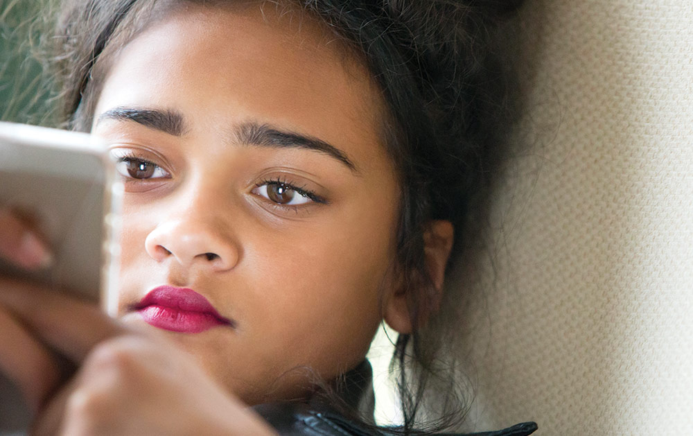 Image of a teen girl looking at iphone concerned about Teen Dating Violence
