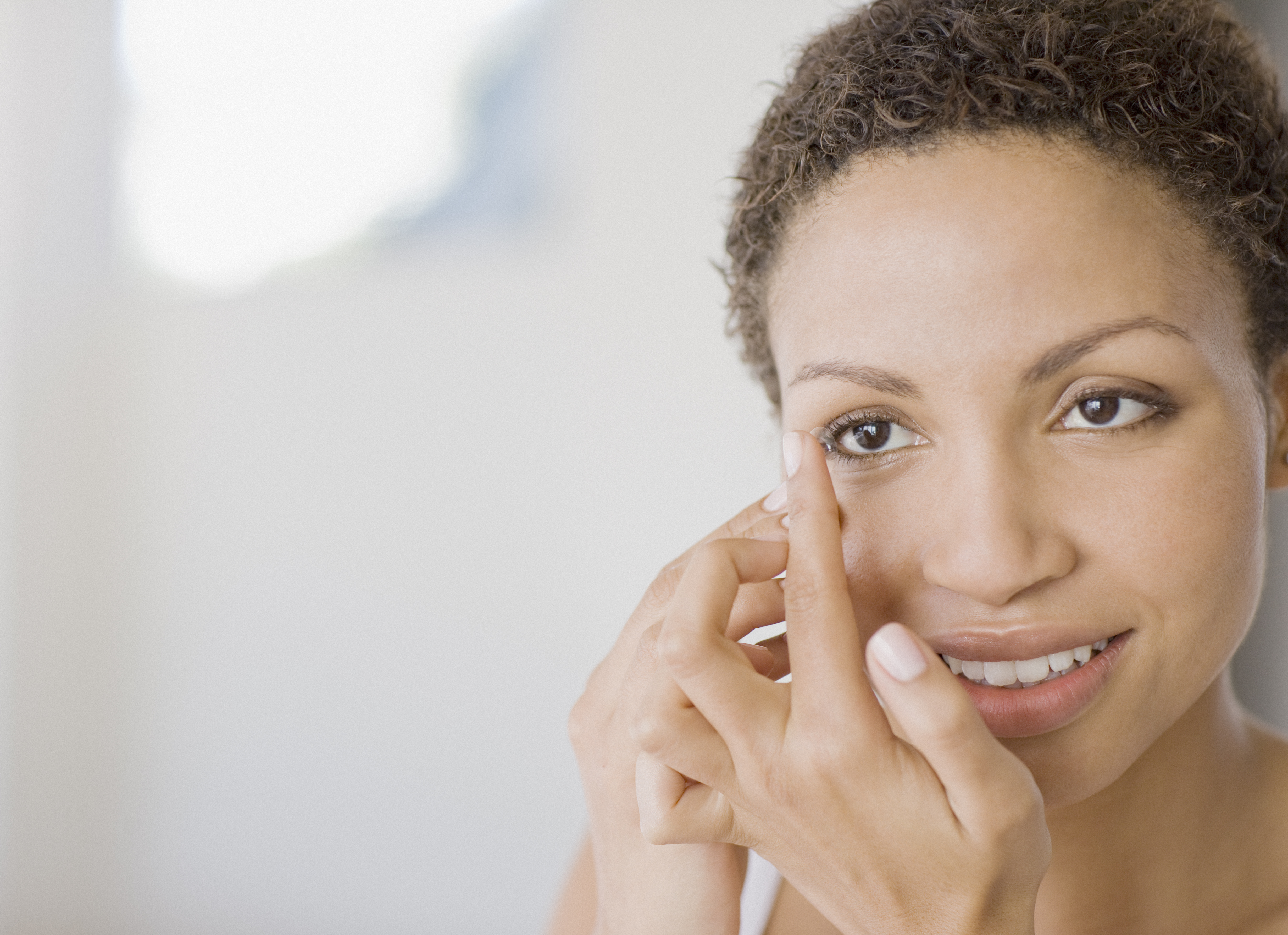 Image of woman inserting contact lens